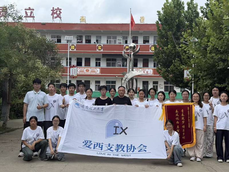 队员与校长在校门前合影，手持爱西会旗与学校赠送的锦旗
